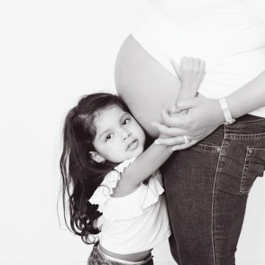 Girl hugs her Mum's pregnant belly