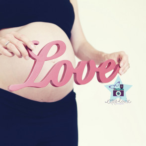 pregnant lady holds love sign in front of bump