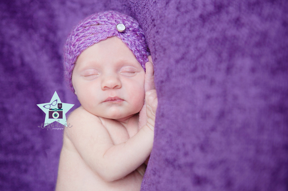 newborn Lucy lies on purple blanket