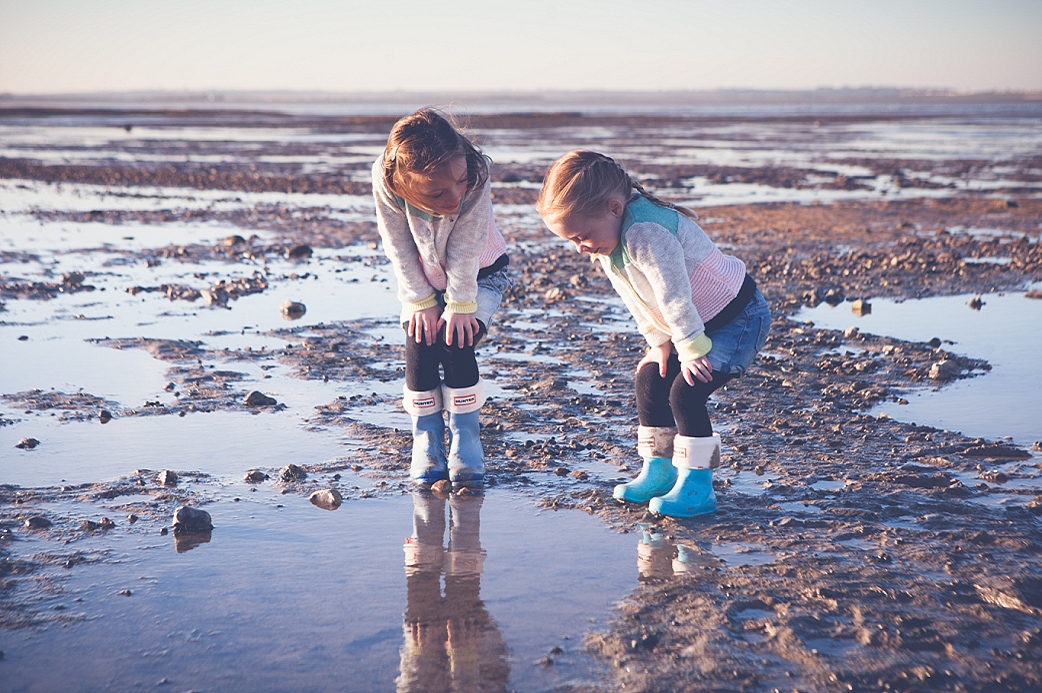 Two girls looking in the rock pool at Seasalter Kent